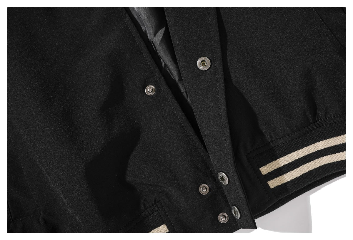 Close-up of the black jacket's snap-button front placket and cream-striped ribbed hem.