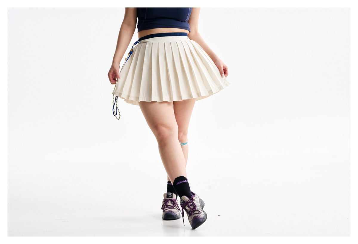 Cropped model wearing a cream pleated athletic skirt with a navy crop top, shown from the front.