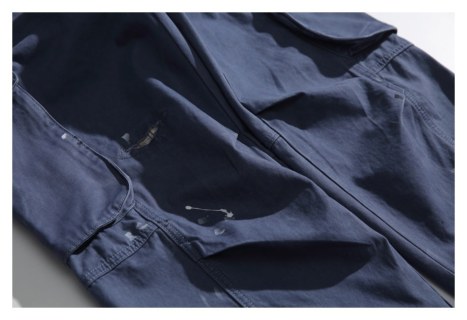 Partial flat-lay view of a navy garment with flap pockets, seams and pale distressed marks.