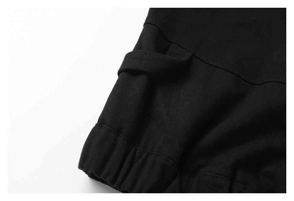 Close-up of a black garment edge with a fabric tab, curved seam, and gathered section.