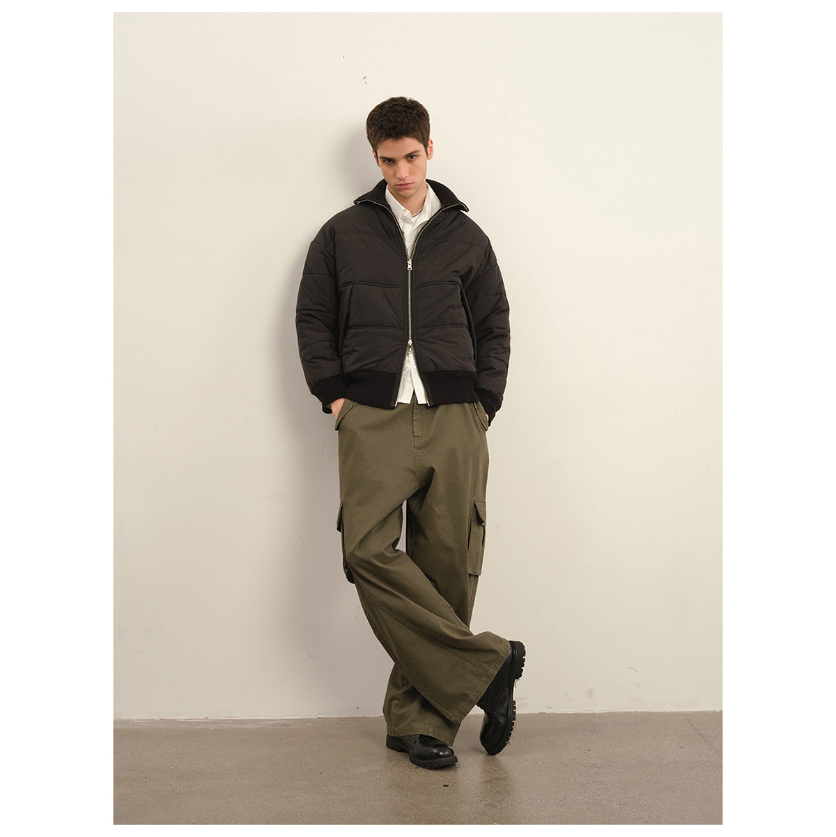 Model wearing a black quilted zip jacket with ribbed hem, olive cargo trousers and black boots.