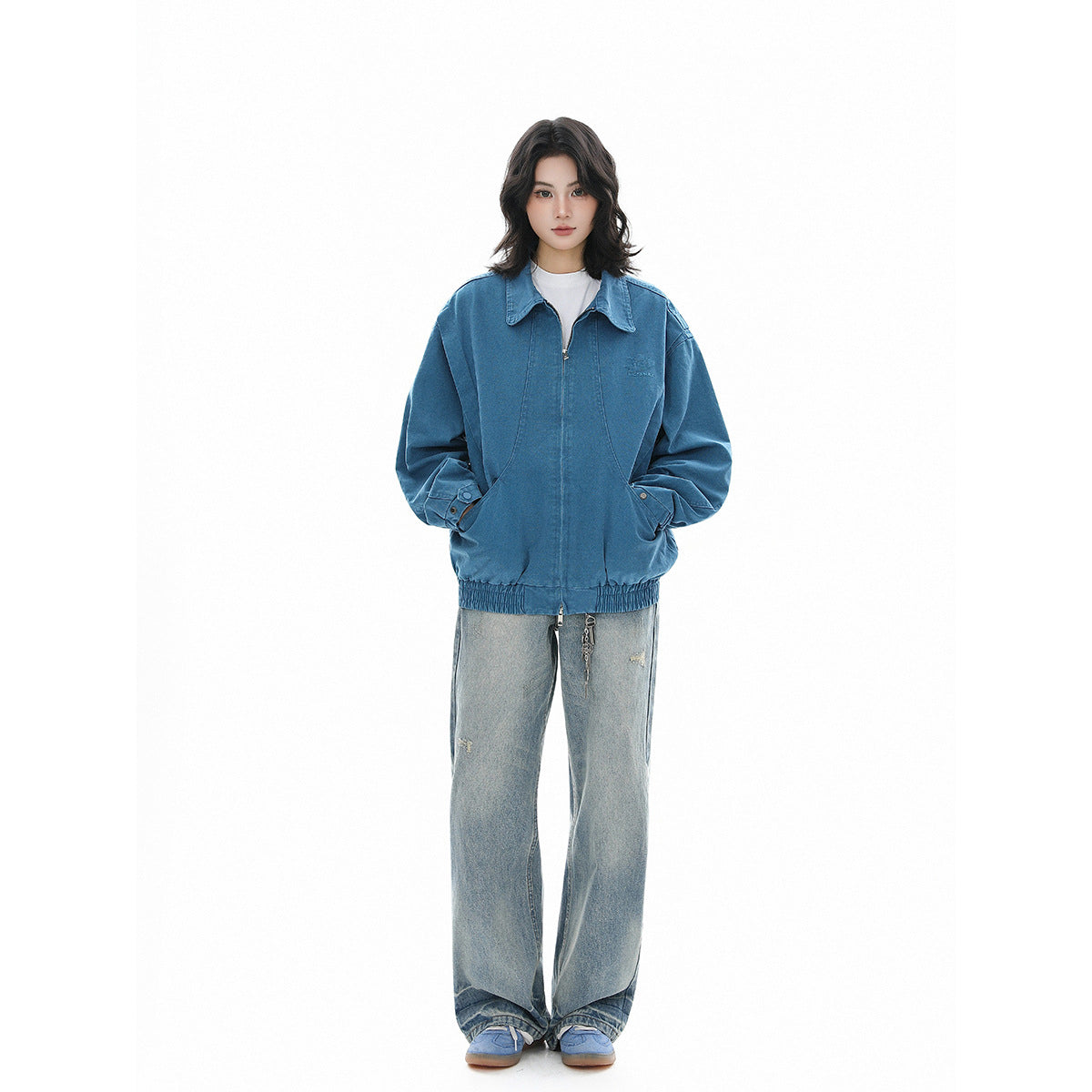 Full-length view of a model wearing a blue zip-front jacket with a pointed collar, roomy sleeves, and gathered hem.