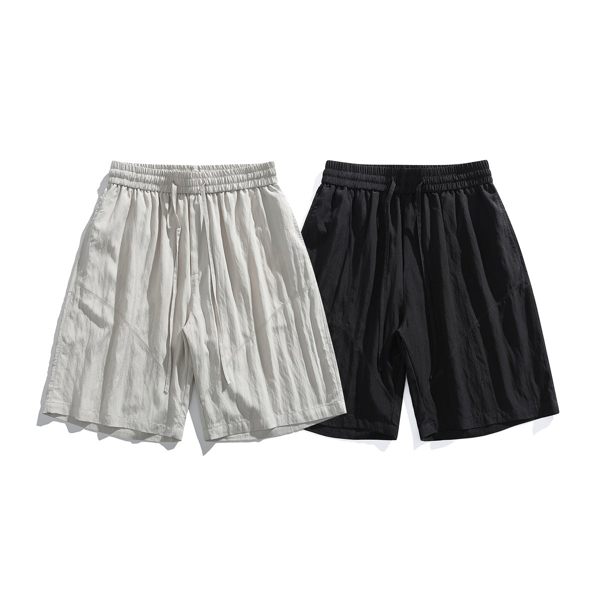 Off-white and black loose shorts shown together from the front, each with a gathered waistband and drawstring.