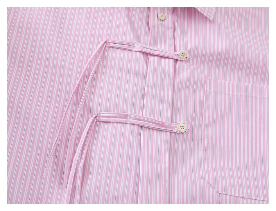Close-up of two decorative button tabs and a chest pocket on a pink striped shirt.