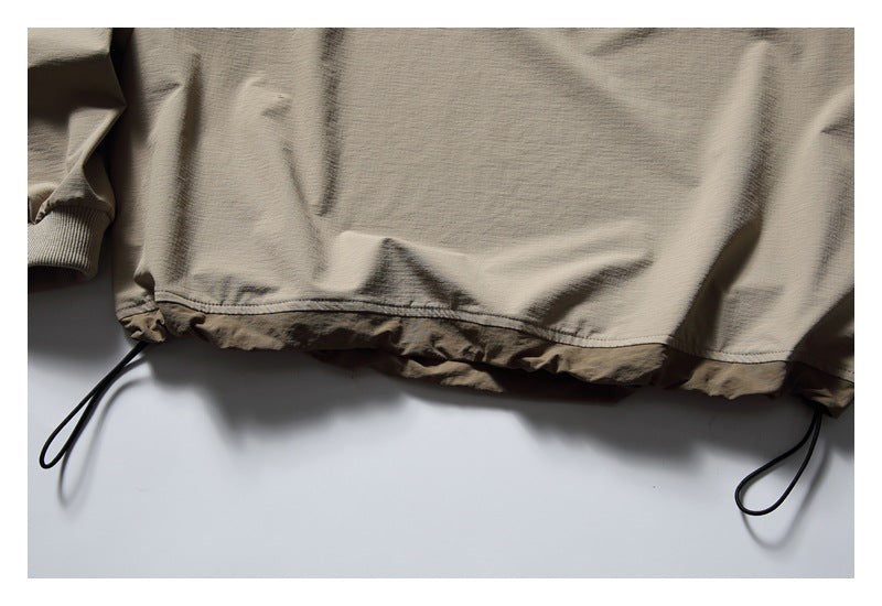 Close-up of the pullover's gathered hem, contrasting lower panel and adjustable black drawcords.