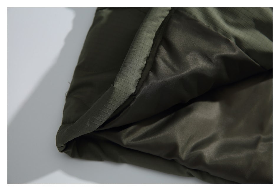 Close-up of the smooth dark lining and stitched edge inside an olive jacket.