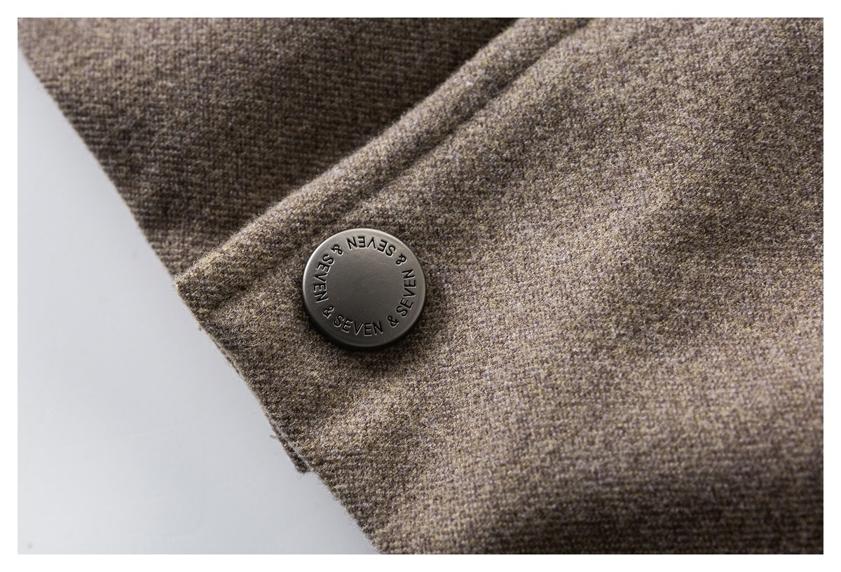 Close-up of a dark branded button on brown textured coat fabric.