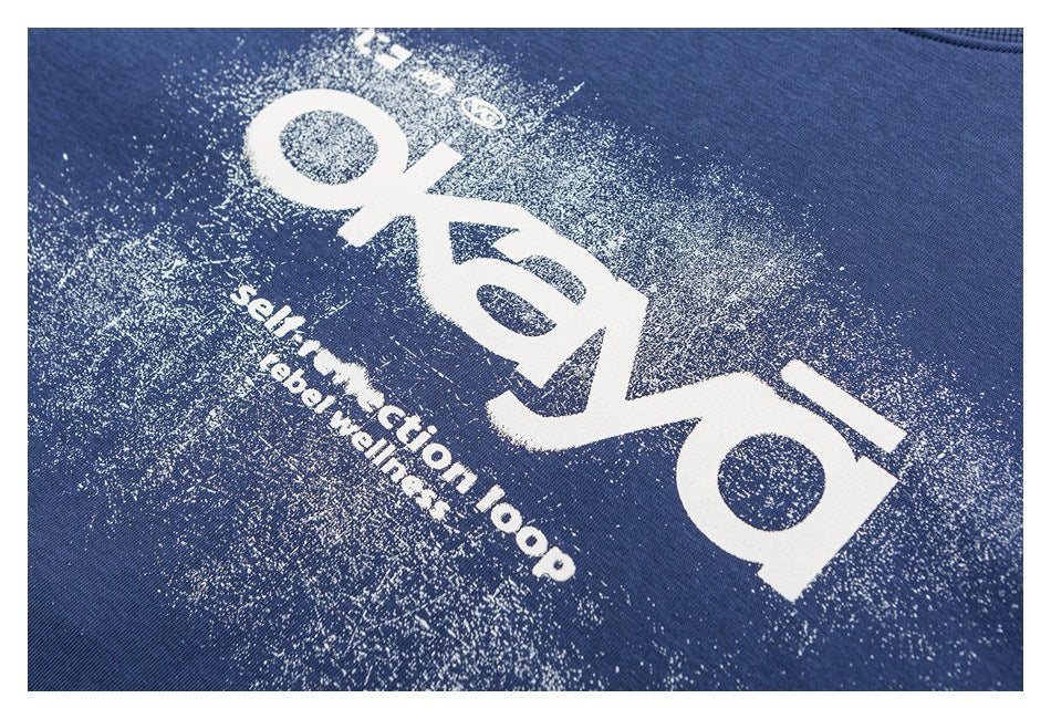Close-up of distressed white lettering printed on blue sweatshirt fabric.