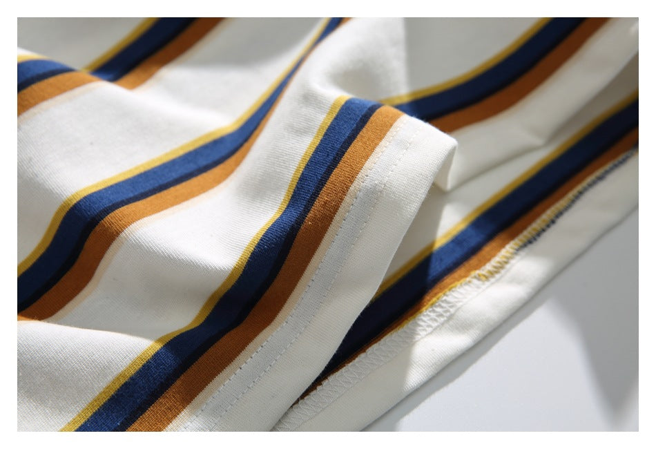 Close-up of the cream T-shirt’s striped sleeve edge and stitched lower hem.