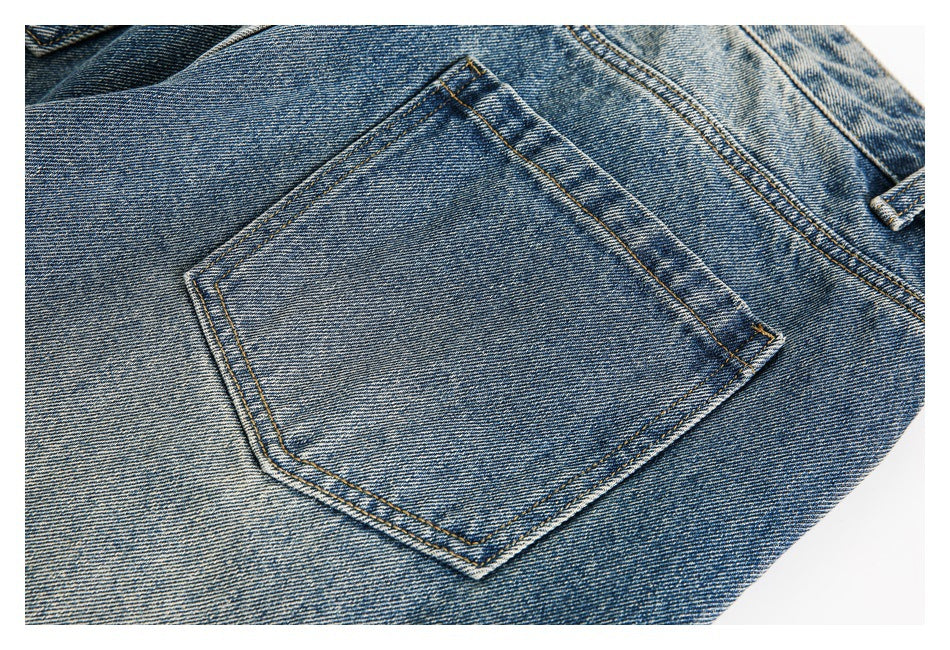 Close-up of a blue denim back pocket with contrast stitching and faded wash.