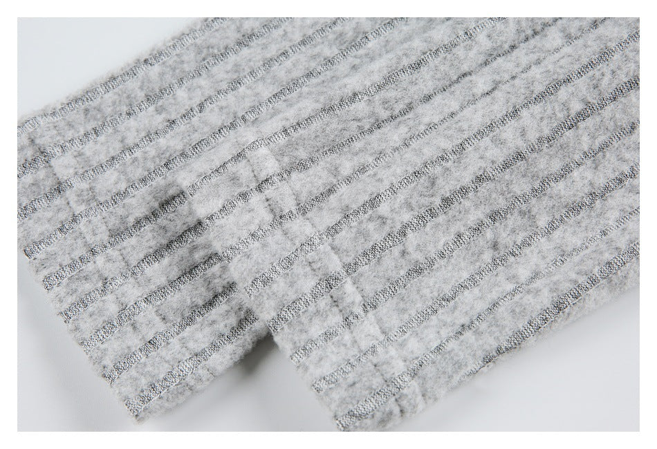 Close-up of the hem of a light gray garment with narrow dark stripes and a fuzzy surface.