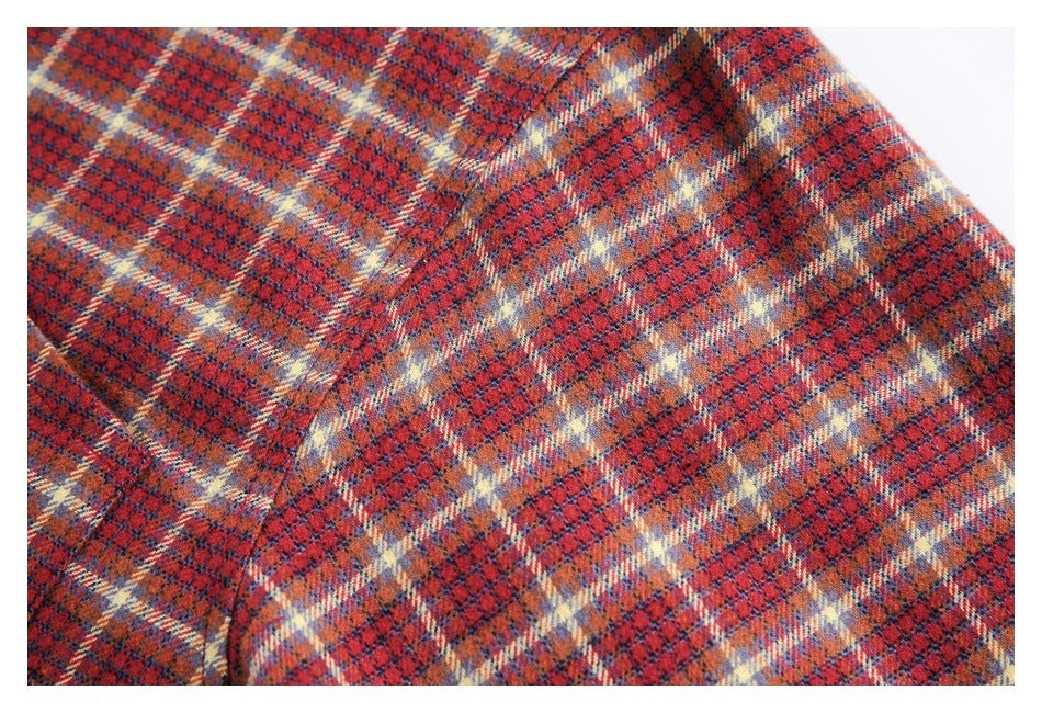 Close-up of red, navy, and cream plaid shirt fabric with a curved stitched seam.
