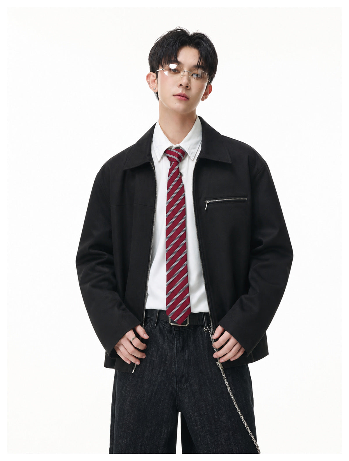 Model wearing an open black collared jacket with a chest zip pocket over a white shirt and red striped tie.