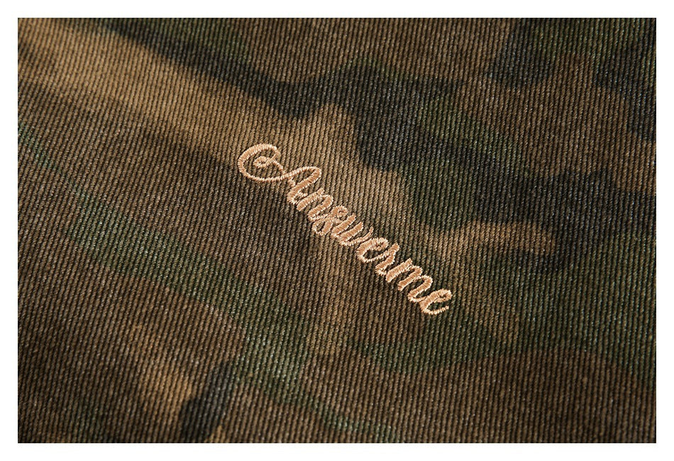 Close-up of pale embroidered script on brown and olive camouflage fabric.