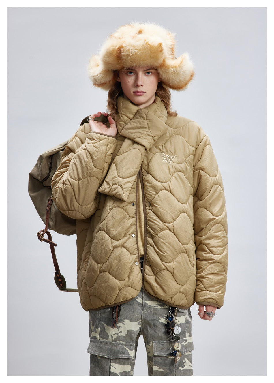 Front view of a model wearing a tan wave-quilted jacket with a padded wrap collar and snap buttons.