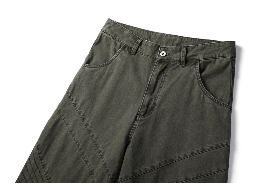 Front view of dark olive-gray pants with curved pockets, belt loops, and angled stitched panels.