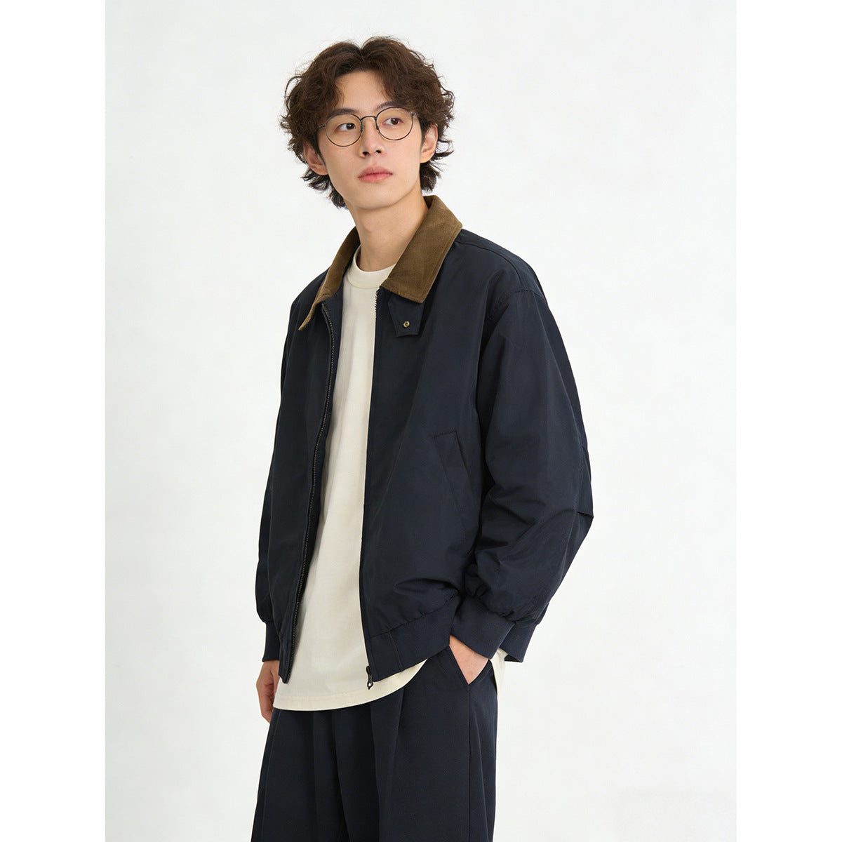 Model in a navy zip jacket with a brown collar, shown at an angle over a cream shirt.