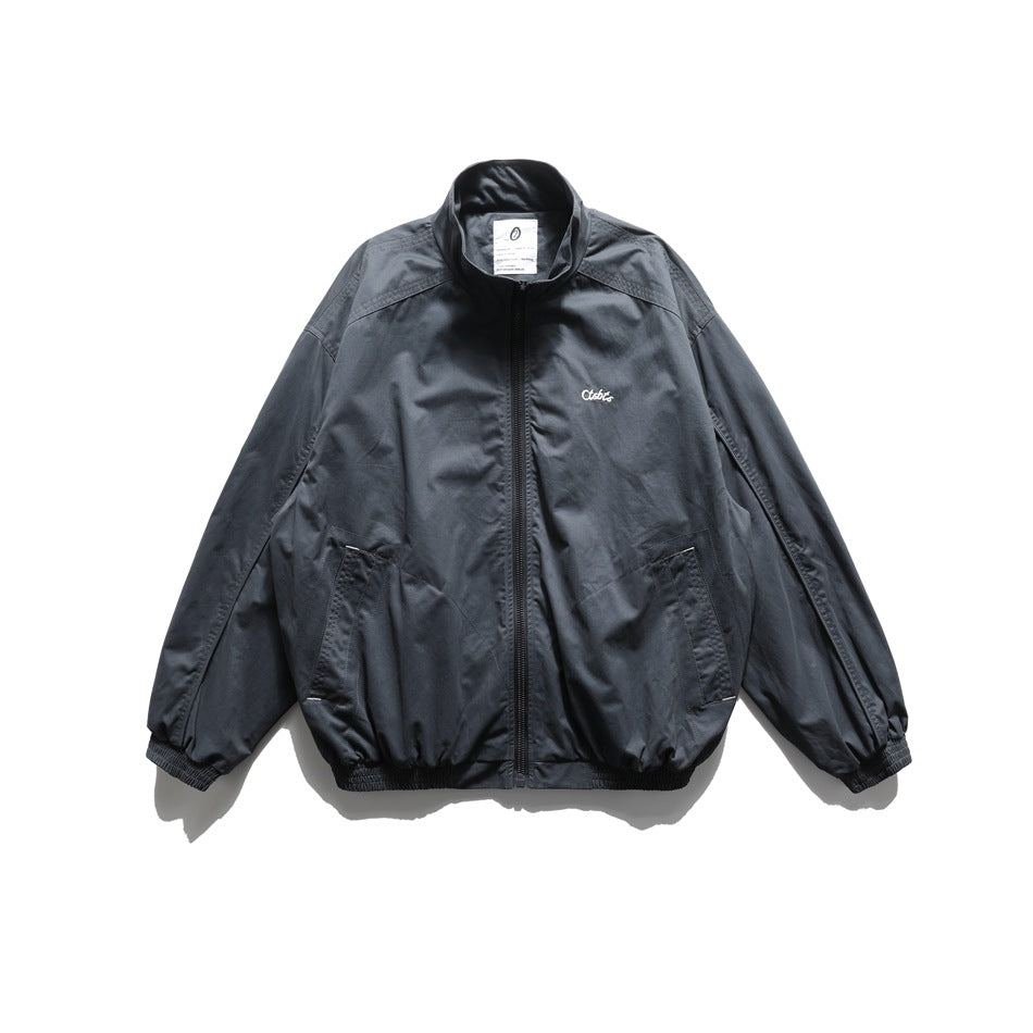Dark slate blue-gray zip-up stand-collar jacket, front flat lay, with small white embroidered logo and side pockets