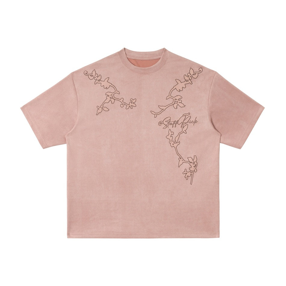 Pink suede-like short-sleeve T-shirt with darker floral vine embroidery and script lettering, flat front view