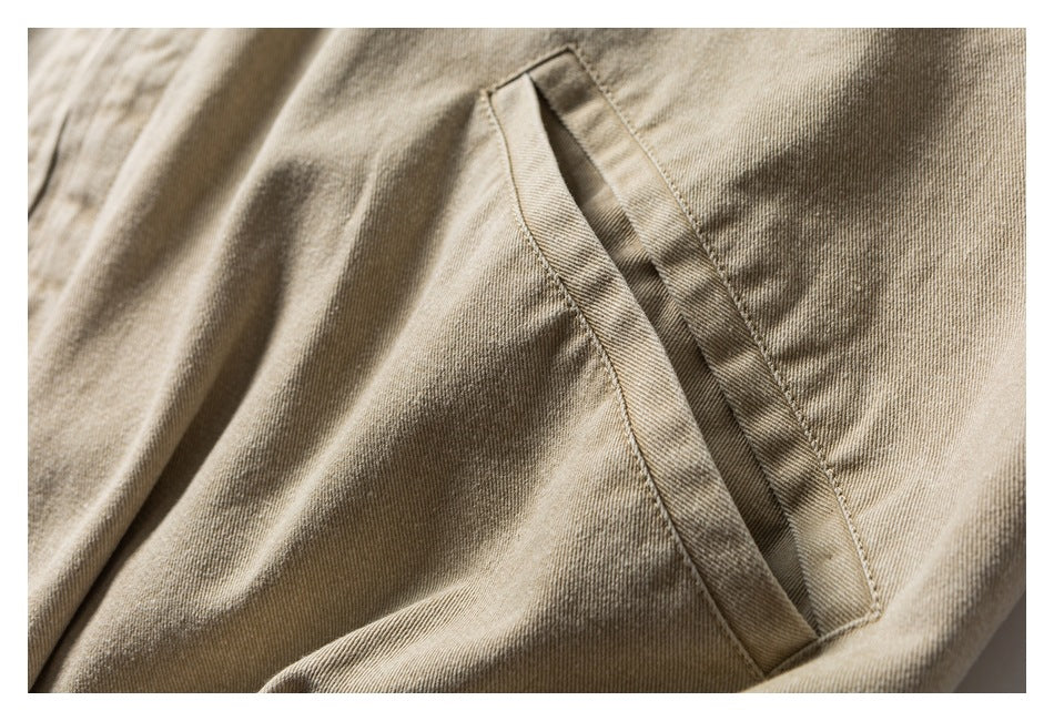 Close-up of a slanted welt pocket on beige twill fabric.