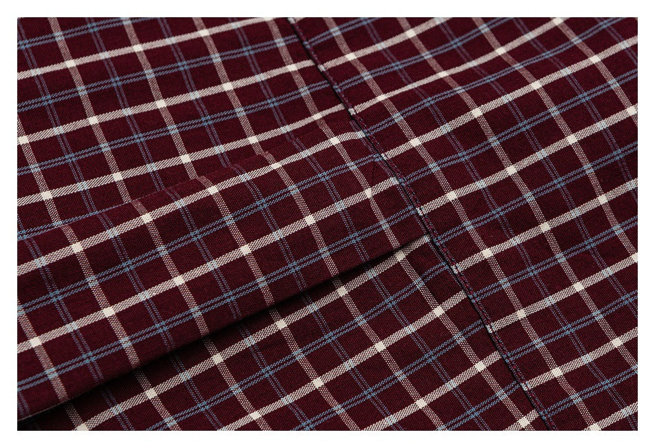 Close-up of a stitched seam across burgundy fabric with a cream and blue plaid pattern.