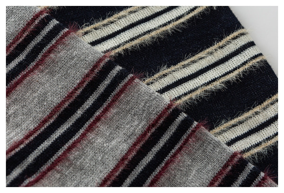 Close-up of striped knit fabric in navy, cream, gray, and burgundy with fuzzy accent lines.