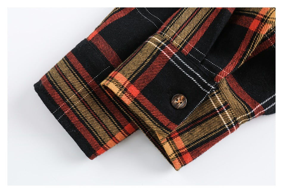 Close-up of a plaid shirt cuff with a brown button and visible stitching.