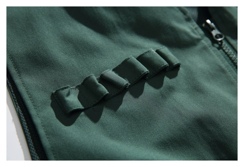 Close-up of a dark green garment showing a row of folded fabric loops beside a zipper.