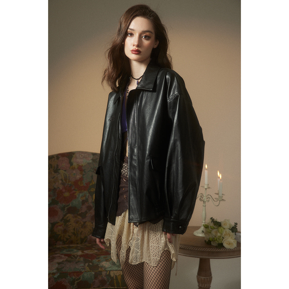 Model wearing an oversized black leather-look jacket with a wide collar, zip front and flap pockets.