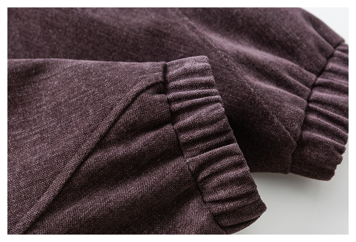 Close-up of dark plum-brown garment fabric with a gathered ribbed cuff and stitched seam.