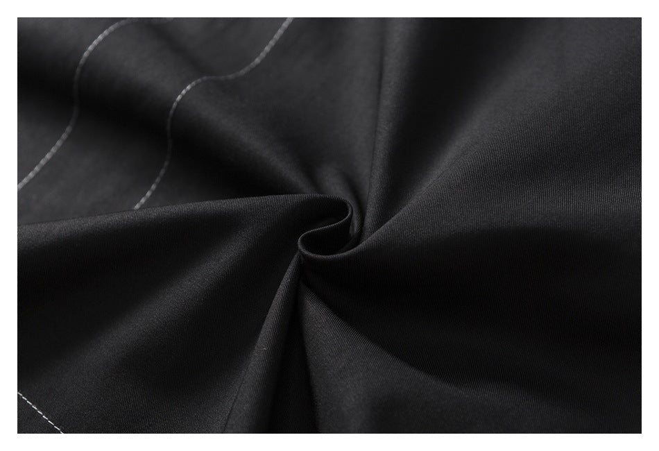 Close-up of draped black fabric with a few curved rows of contrast stitching.