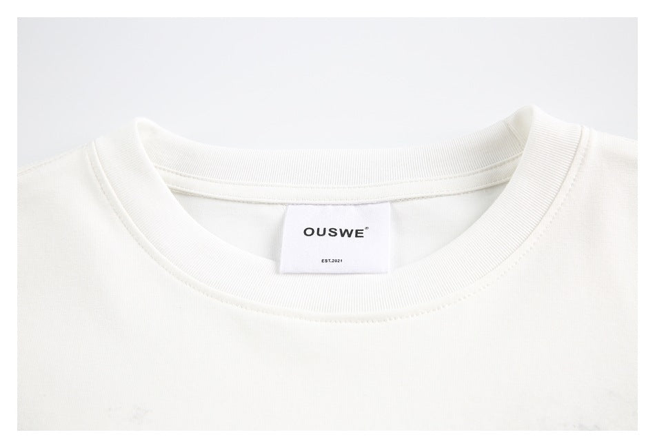 Close-up of the ribbed crew neck and OUSWE label on an off-white T-shirt.