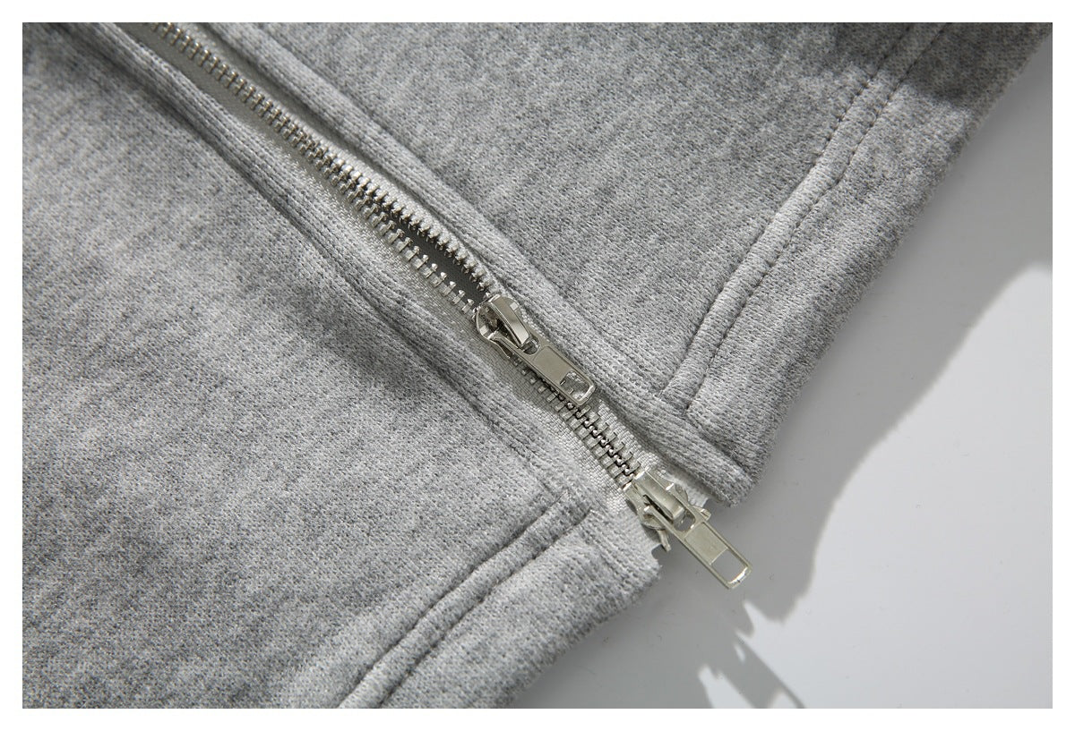 Close-up of silver zipper sliders and stitching on heather gray knit fabric.