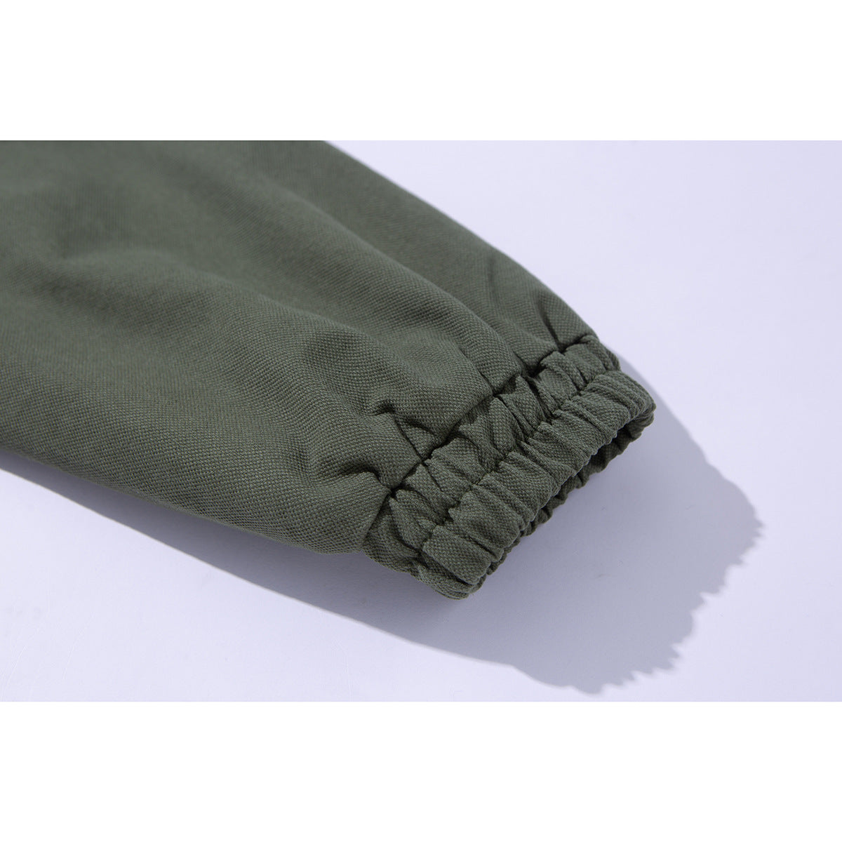Close-up of an olive jacket sleeve ending in a gathered elastic cuff.