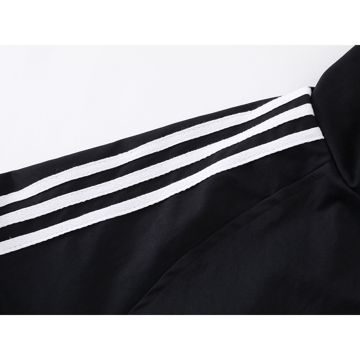 Close-up of three white stripes running along the black jacket sleeve.
