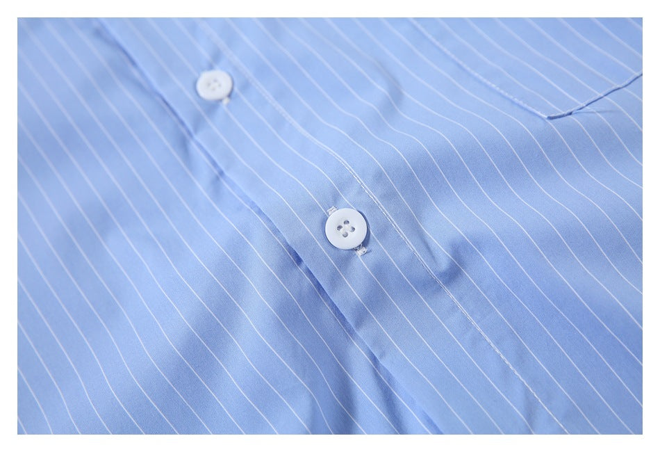 Close-up of a light blue shirt with thin white pinstripes, showing white buttons and the front placket.