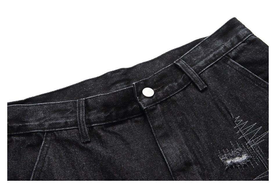 Close-up of the waistband and button on black denim shorts, with a distressed detail at the side.