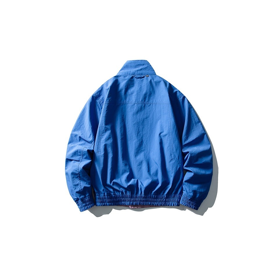 Back view of a bright blue jacket with a stand collar, long sleeves, and elasticated cuffs and hem.