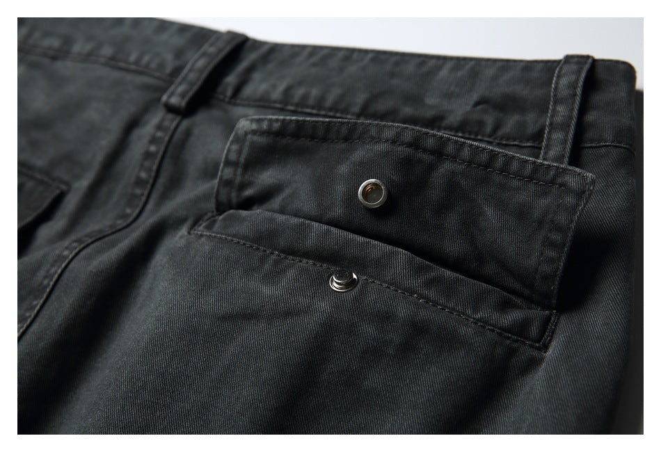 Close-up of a charcoal trouser flap pocket with a metal snap closure and belt loops.