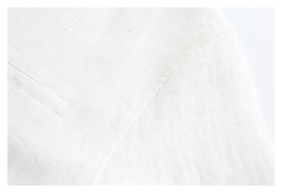 Close-up of an off-white garment showing a curved seam and fine, subtly slubbed texture.