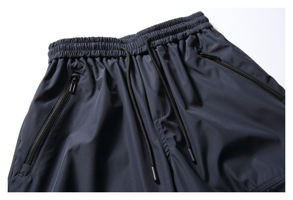 Close-up of navy pants showing the elastic drawstring waist and two angled zippered front pockets.