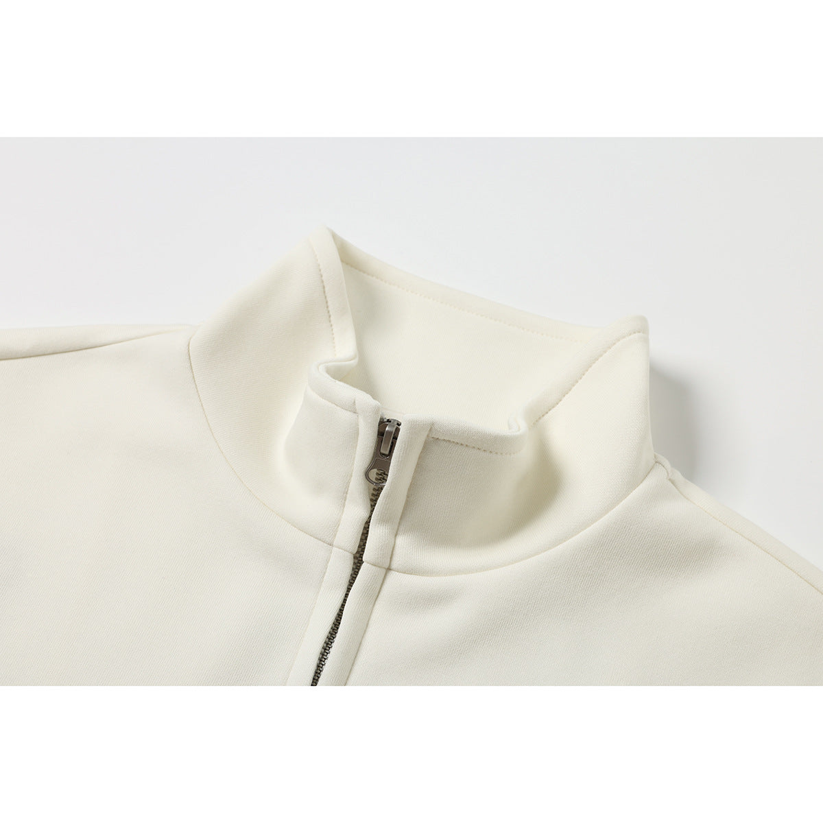 Close-up of an ivory jacket's stand collar and partially open metal front zipper.