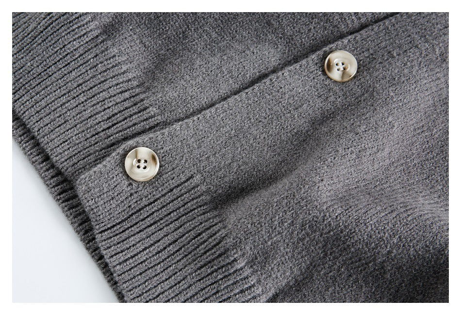Close-up of a charcoal gray cardigan’s button placket, cream buttons, and ribbed edge.