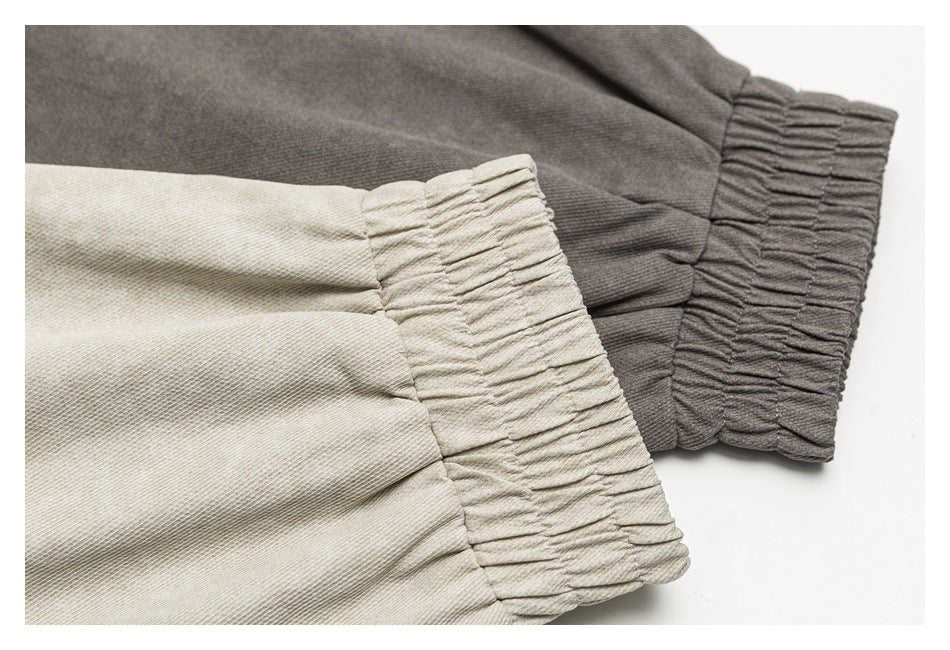 Close-up of gathered elastic cuffs on light beige and charcoal gray garments.
