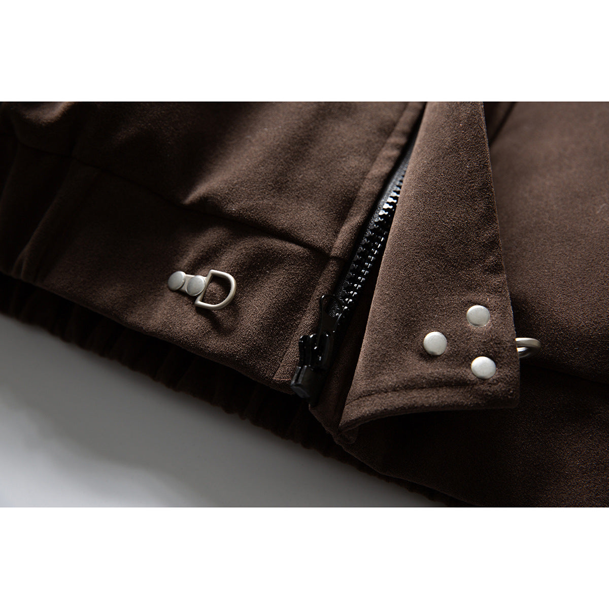 Close-up of a dark brown jacket's black zipper, silver snaps, and metal clasp.