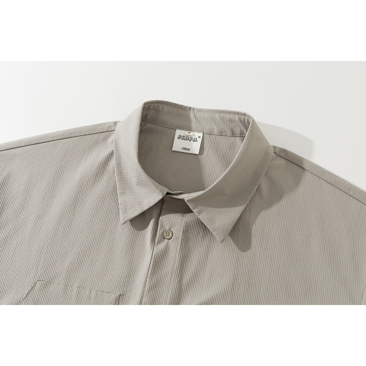 Close-up of a light gray short-sleeve shirt’s pointed collar, button placket, and fine textured fabric.