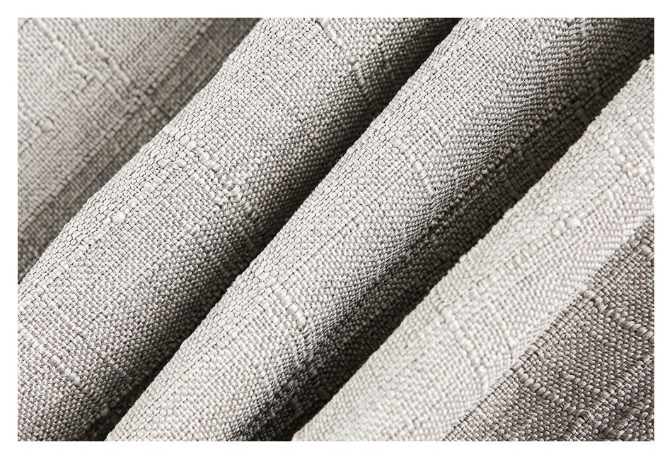 Extreme close-up of the light beige garment's woven-looking textured fabric and folds.