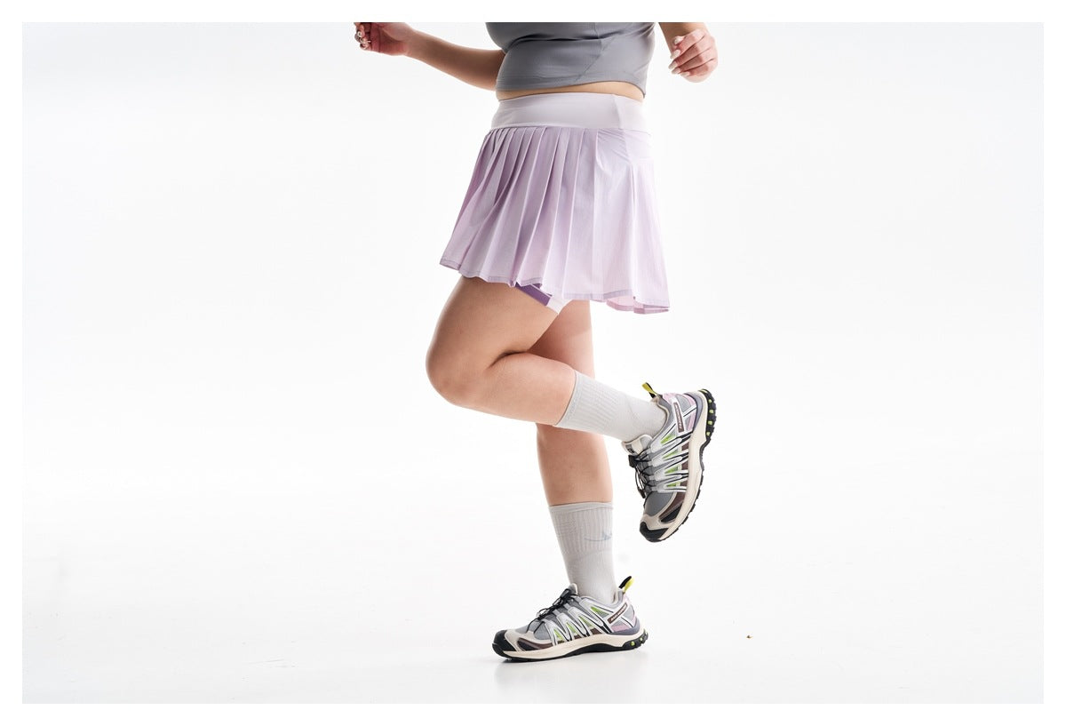 Cropped view of a woman in a lilac pleated skort and white knee socks, posing in athletic shoes.