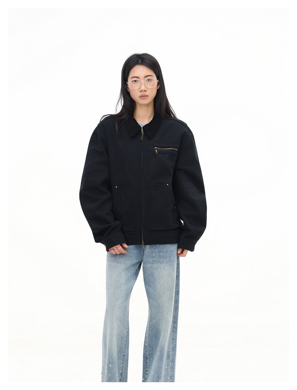 Front view of a model wearing a zipped black oversized jacket with a pointed collar, zip chest pocket, and two patch pockets.