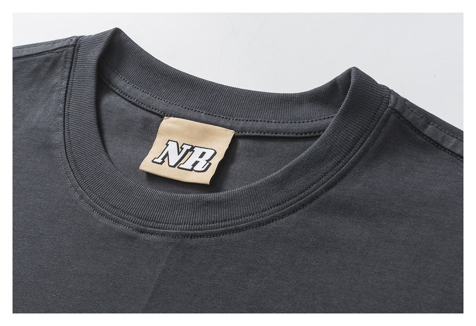 Close-up of a charcoal T-shirt's ribbed crew neck and beige inner label marked “NB.”